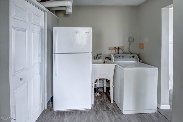 washroom featuring laundry area, wood finished floors, washer / dryer, and baseboards