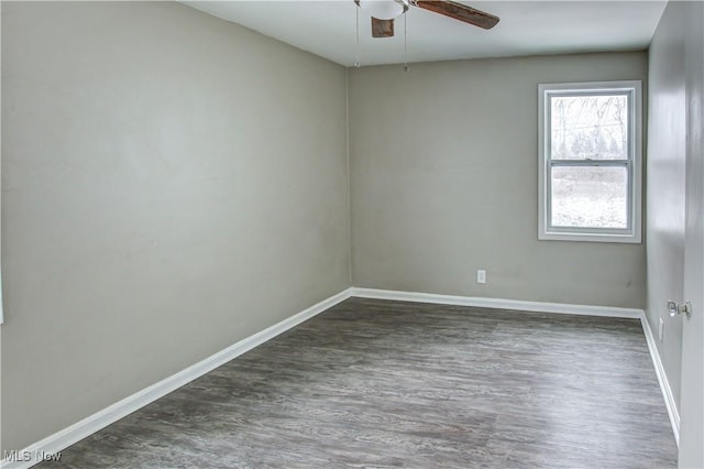 spare room featuring ceiling fan, dark wood-style flooring, and baseboards