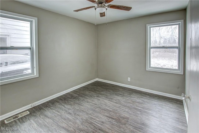 unfurnished room with a ceiling fan, visible vents, baseboards, and wood finished floors