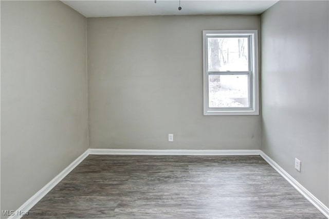 spare room with dark wood-style flooring and baseboards