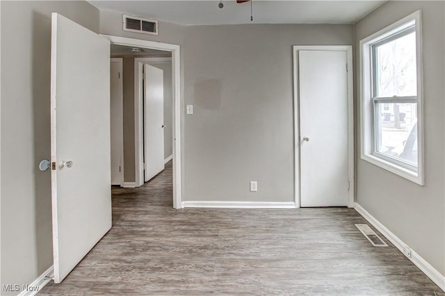 unfurnished bedroom with visible vents, baseboards, and wood finished floors