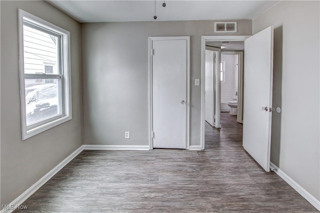 unfurnished room featuring wood finished floors, visible vents, and baseboards