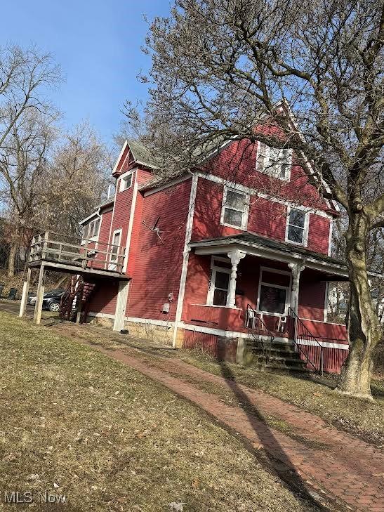 view of front facade with a porch, a front yard, and brick siding