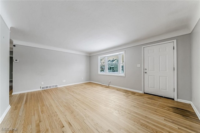 unfurnished living room with baseboards, visible vents, and light wood-style floors