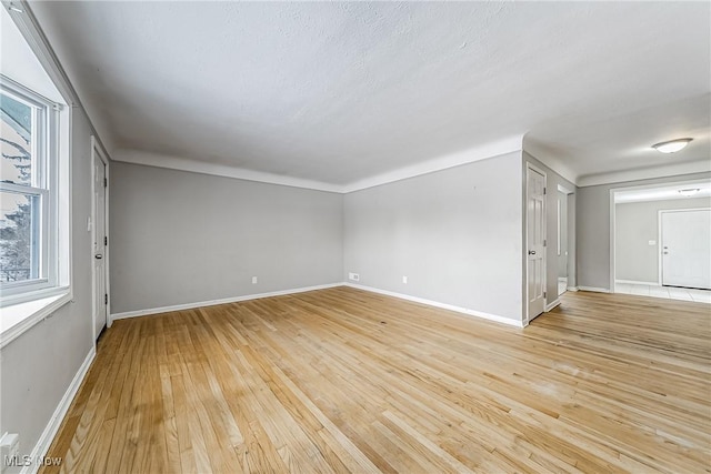 empty room with plenty of natural light, light wood-style flooring, and baseboards