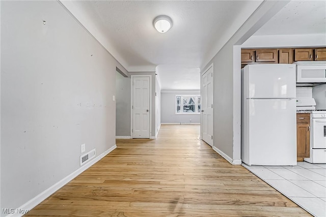 kitchen with baseboards, white appliances, visible vents, and light wood-style floors