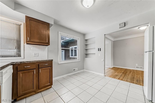 kitchen featuring built in features, light tile patterned floors, visible vents, backsplash, and white appliances