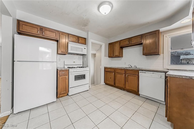 kitchen with white appliances, decorative backsplash, brown cabinets, and a sink