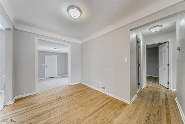 spare room with visible vents, light wood-style flooring, and baseboards