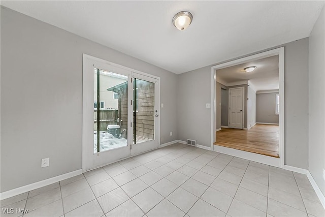 empty room featuring light tile patterned floors, visible vents, and baseboards