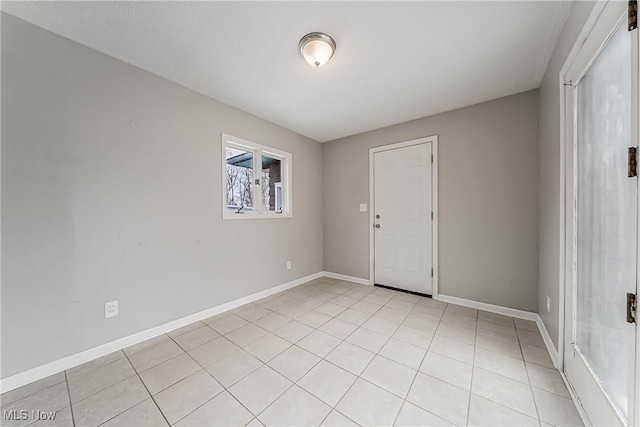 spare room featuring light tile patterned flooring and baseboards