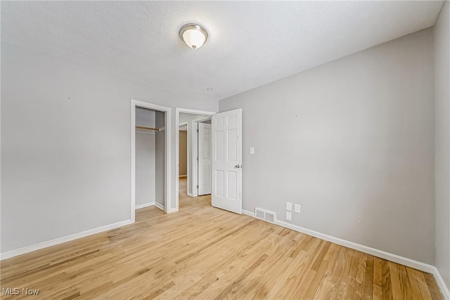 unfurnished bedroom with baseboards, a closet, visible vents, and light wood-style floors