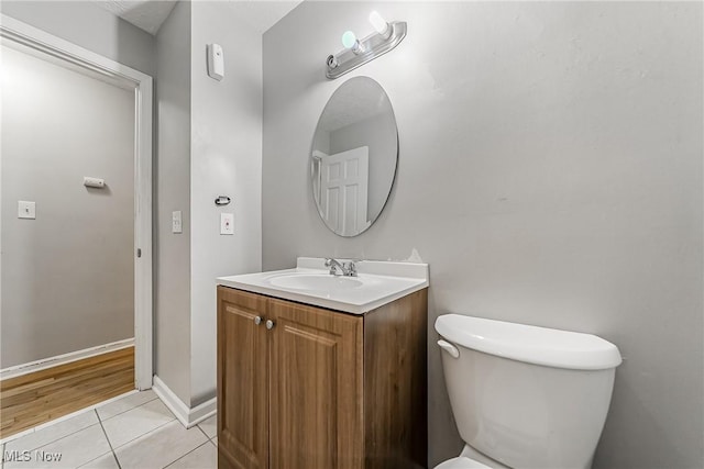 bathroom featuring baseboards, vanity, toilet, and tile patterned floors