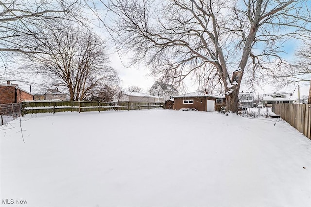 yard covered in snow with an outbuilding and a fenced backyard