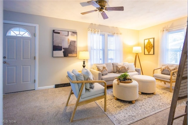 carpeted living area with a ceiling fan and baseboards