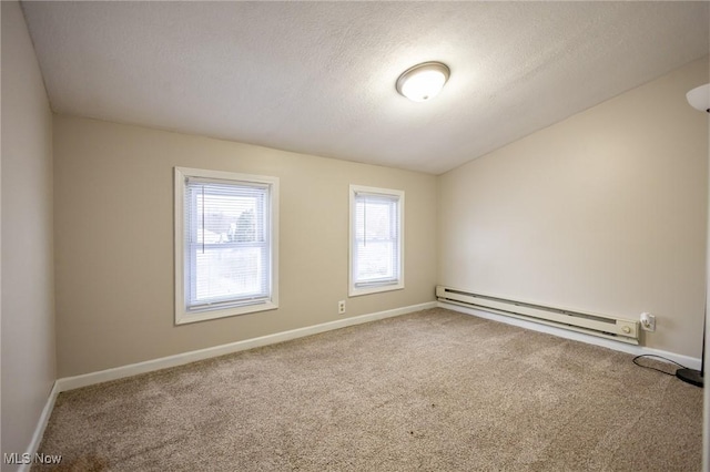 empty room featuring a baseboard heating unit, a textured ceiling, carpet, and baseboards