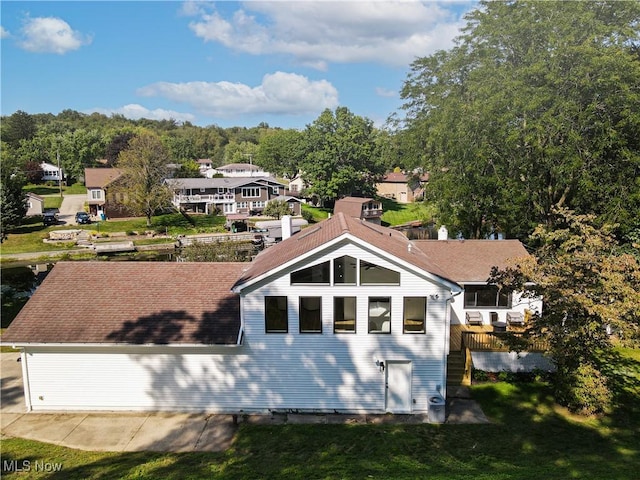 rear view of house featuring a yard and a shingled roof