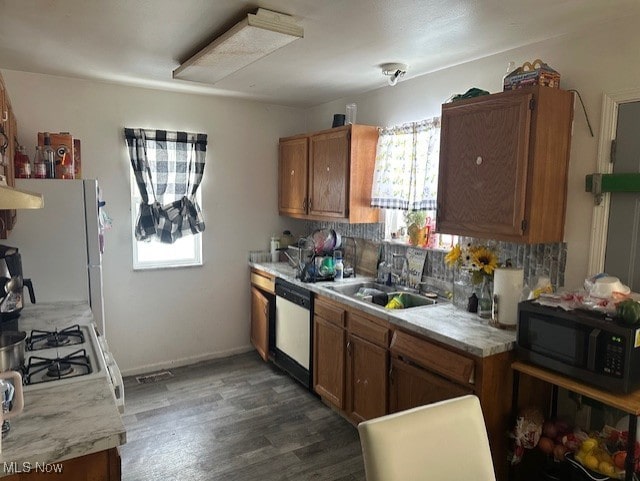 kitchen with white appliances, light countertops, a sink, and brown cabinetry