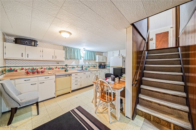 kitchen with a sink, white appliances, white cabinets, and light countertops