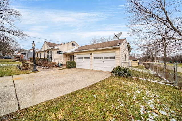 view of side of home featuring an attached garage, a lawn, fence, and concrete driveway