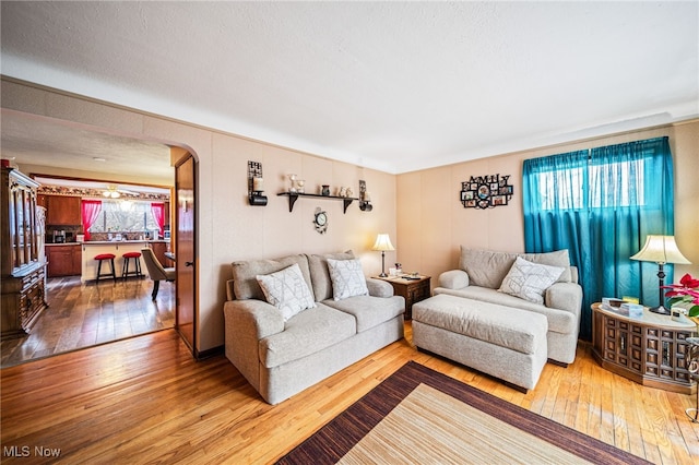 living room featuring arched walkways, hardwood / wood-style floors, and a wealth of natural light