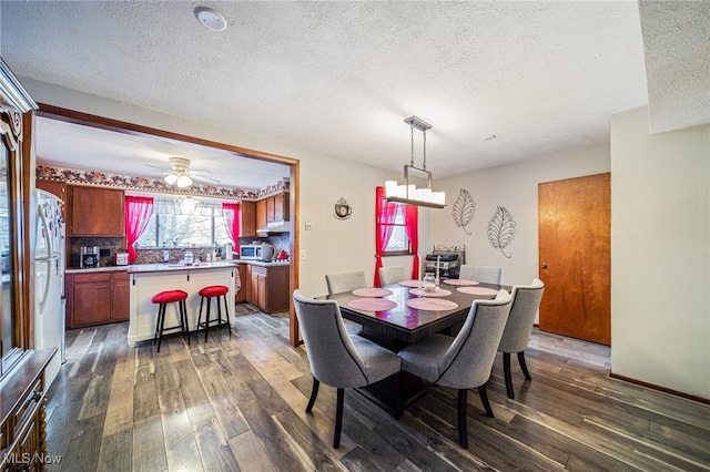 dining room featuring a textured ceiling, a ceiling fan, and dark wood-style flooring