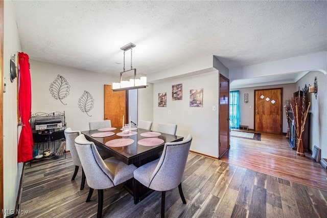 dining room with a textured ceiling, a chandelier, and hardwood / wood-style floors