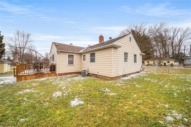 rear view of house featuring a deck, central AC, fence, a yard, and a chimney