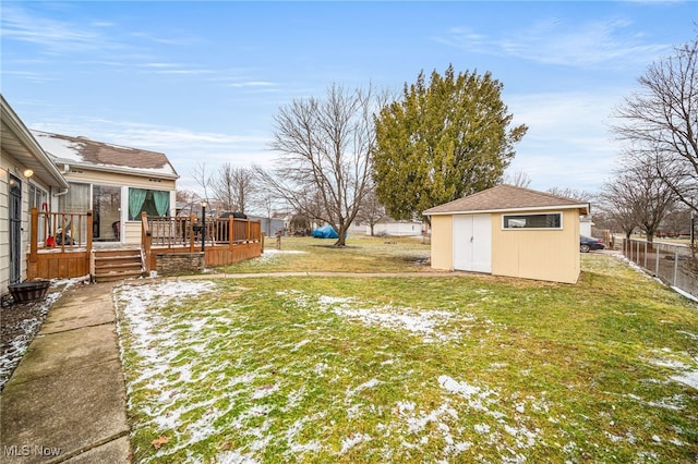 view of yard featuring an outbuilding, fence, a wooden deck, and a storage unit