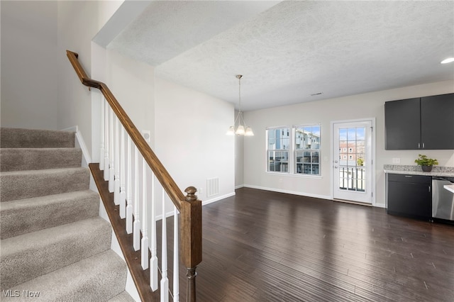 stairway with a textured ceiling, wood finished floors, and visible vents