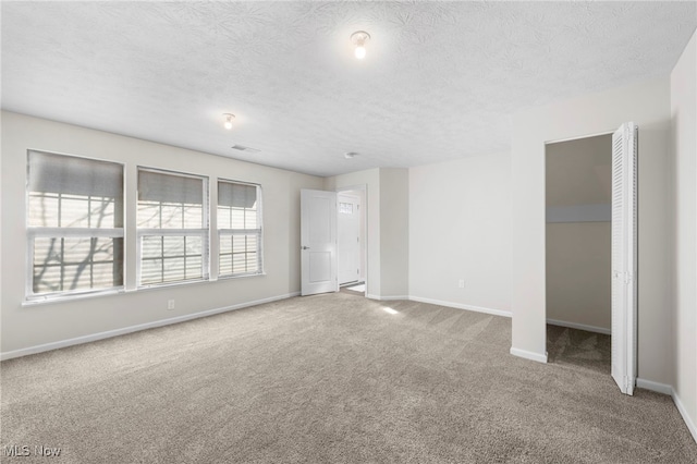 unfurnished bedroom with carpet, visible vents, baseboards, and a textured ceiling