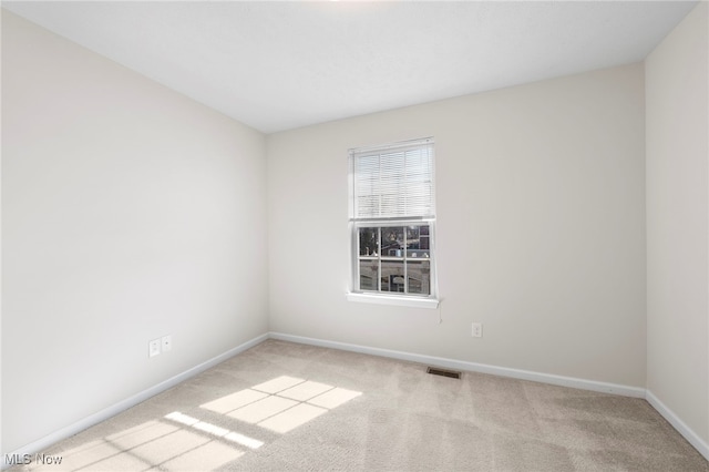 empty room with carpet, visible vents, and baseboards