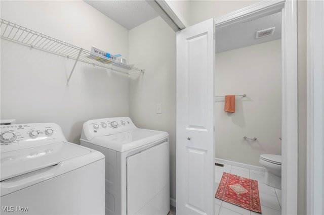 laundry area featuring laundry area, visible vents, washer and clothes dryer, baseboards, and tile patterned flooring