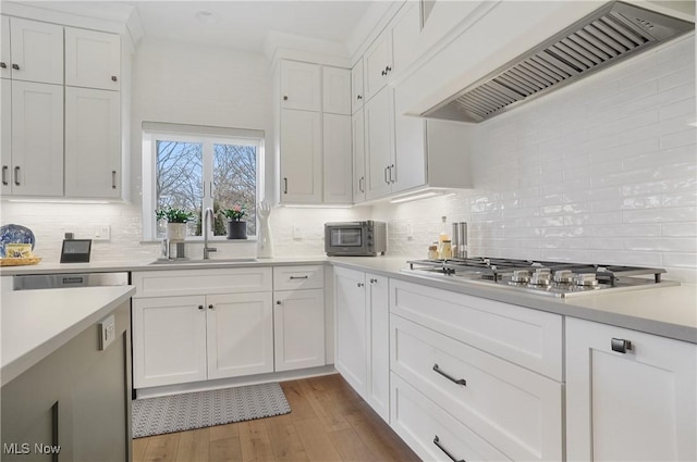 kitchen with light countertops, premium range hood, stainless steel gas stovetop, white cabinetry, and a sink