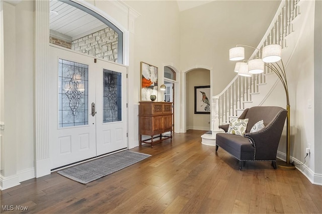 entryway featuring hardwood / wood-style flooring, baseboards, stairs, and arched walkways