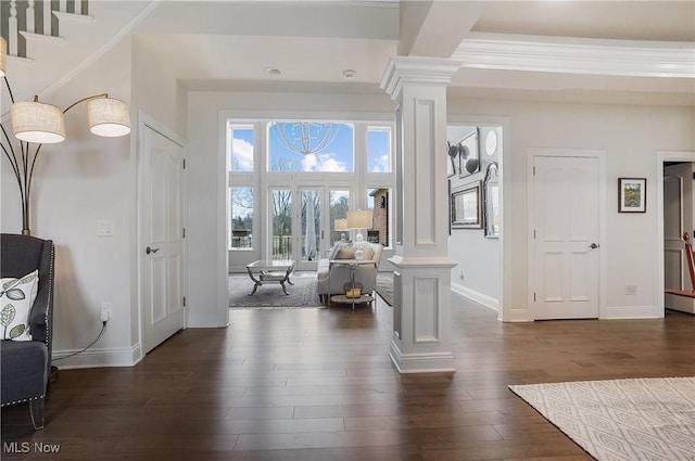 foyer entrance with dark wood finished floors, decorative columns, and baseboards