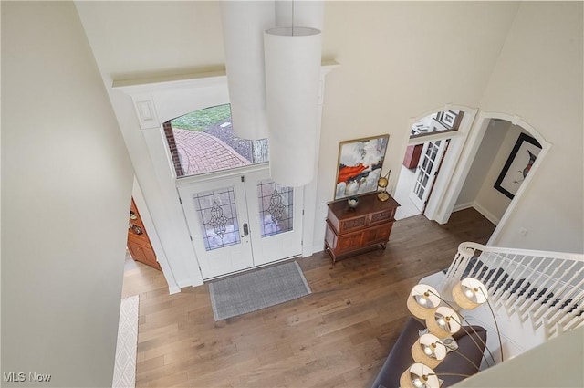 entryway with stairs, a high ceiling, wood finished floors, and french doors