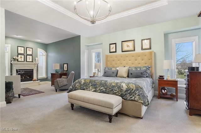 carpeted bedroom with a chandelier, a tray ceiling, a glass covered fireplace, and crown molding