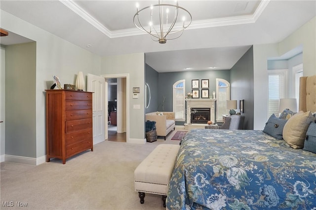 bedroom featuring light carpet, baseboards, a raised ceiling, a glass covered fireplace, and a notable chandelier