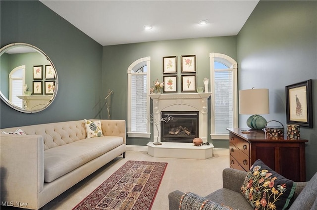 carpeted living room featuring a glass covered fireplace and baseboards