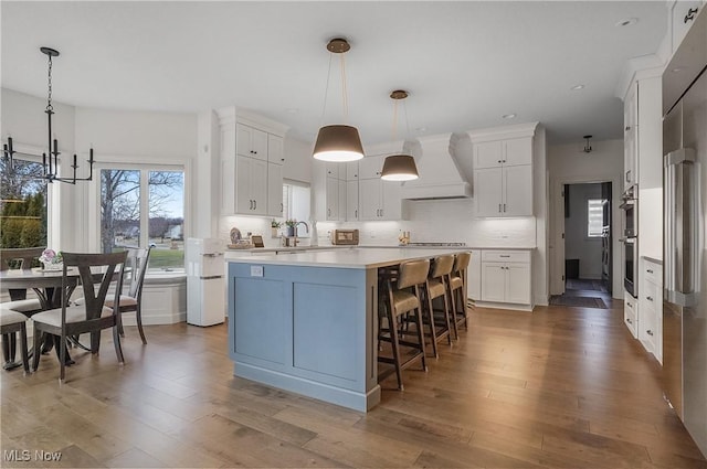 kitchen featuring a kitchen island, backsplash, custom exhaust hood, and wood finished floors