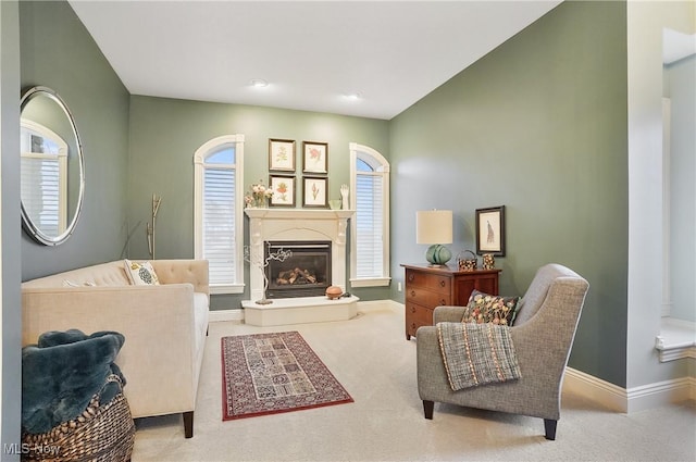 carpeted living area with baseboards, a wealth of natural light, and a glass covered fireplace