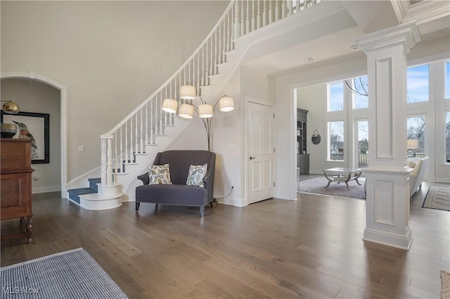 foyer with ornate columns, stairway, a high ceiling, baseboards, and hardwood / wood-style flooring