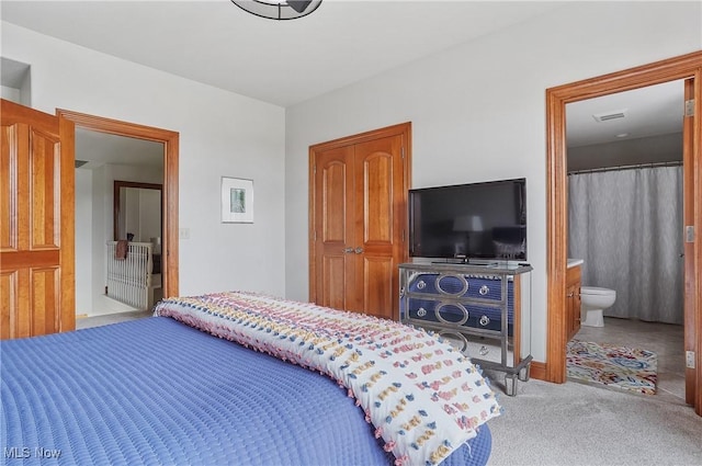 carpeted bedroom with visible vents and connected bathroom