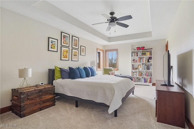 bedroom featuring carpet floors, a raised ceiling, ceiling fan, and baseboards