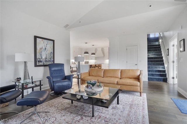 living room with baseboards, visible vents, stairway, wood finished floors, and vaulted ceiling