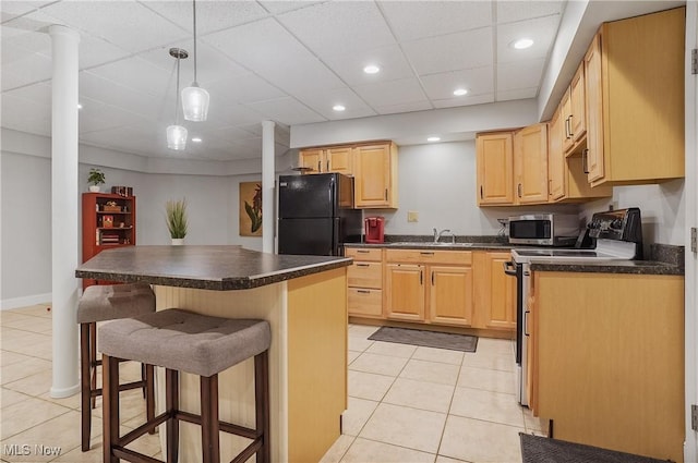 kitchen featuring stainless steel appliances, dark countertops, a sink, and a kitchen breakfast bar