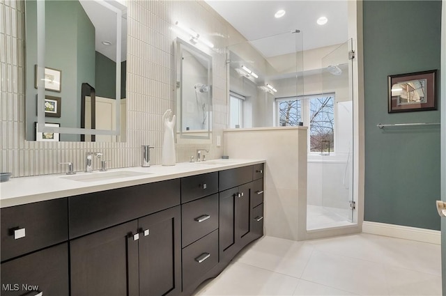 bathroom with double vanity, a tile shower, a sink, and tile patterned floors