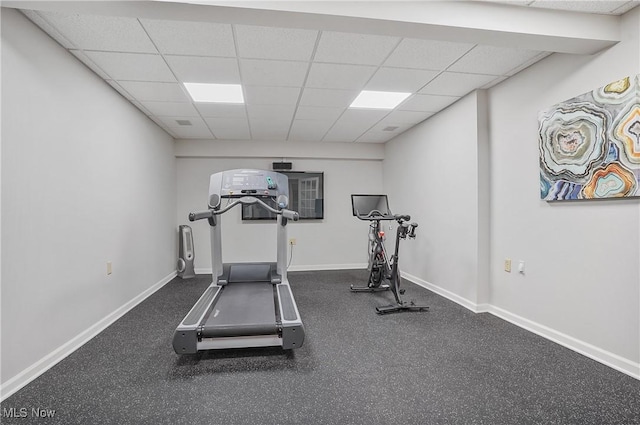 workout area featuring a paneled ceiling and baseboards