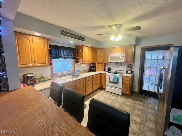 kitchen featuring a wealth of natural light, white appliances, light countertops, and a sink